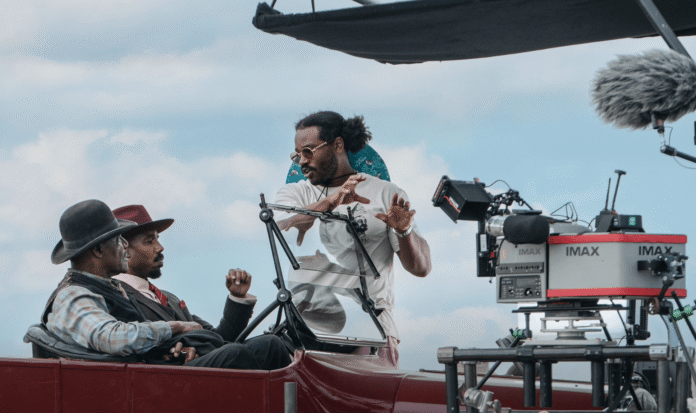 Ryan Coogler directing actors on set beside an IMAX camera, reflecting his journey from college athlete to Oscar-winning filmmaker.
