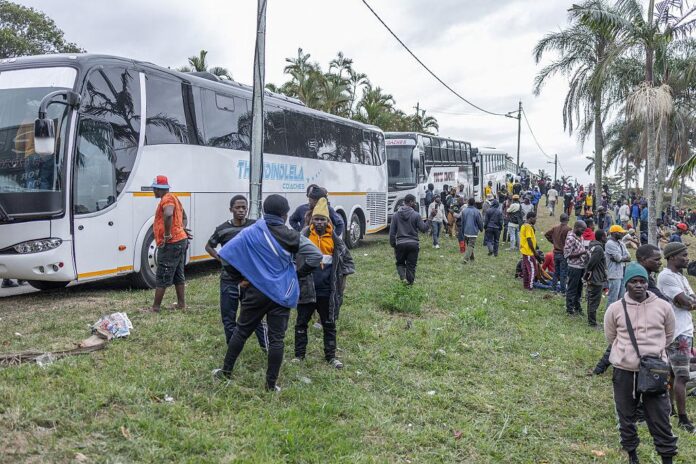Migrants wait to board a bus from South Africa to Harare, Zimbabwe, as thousands of foreign nationals return home amid increased immigration enforcement and anti-immigrant tensions.