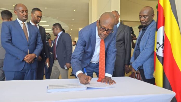 Gen. Henry Tumukunde signs an agreement in Mogadishu as officials look on. Photo Uganda Embassy in Somalia